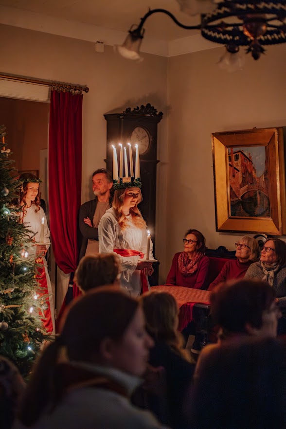 Lucia-neito kynttiläkruunussaan yleisön keskellä joulukodissa